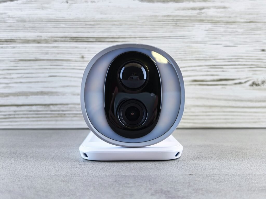 Caméra extérieure sans fil : caméra de surveillance blanche à batterie, vue de face sur son socle (photo d’illustration)