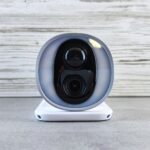 Caméra extérieure sans fil : caméra de surveillance blanche à batterie, vue de face sur son socle (photo d’illustration)