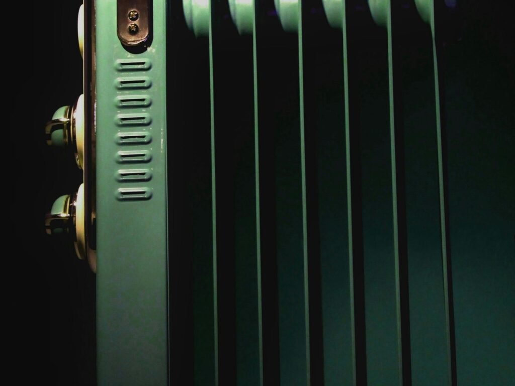Radiateur bain d'huile : radiateur à bain d'huile vert à ailettes avec ses boutons de réglage, en gros plan (photo d’illustration)